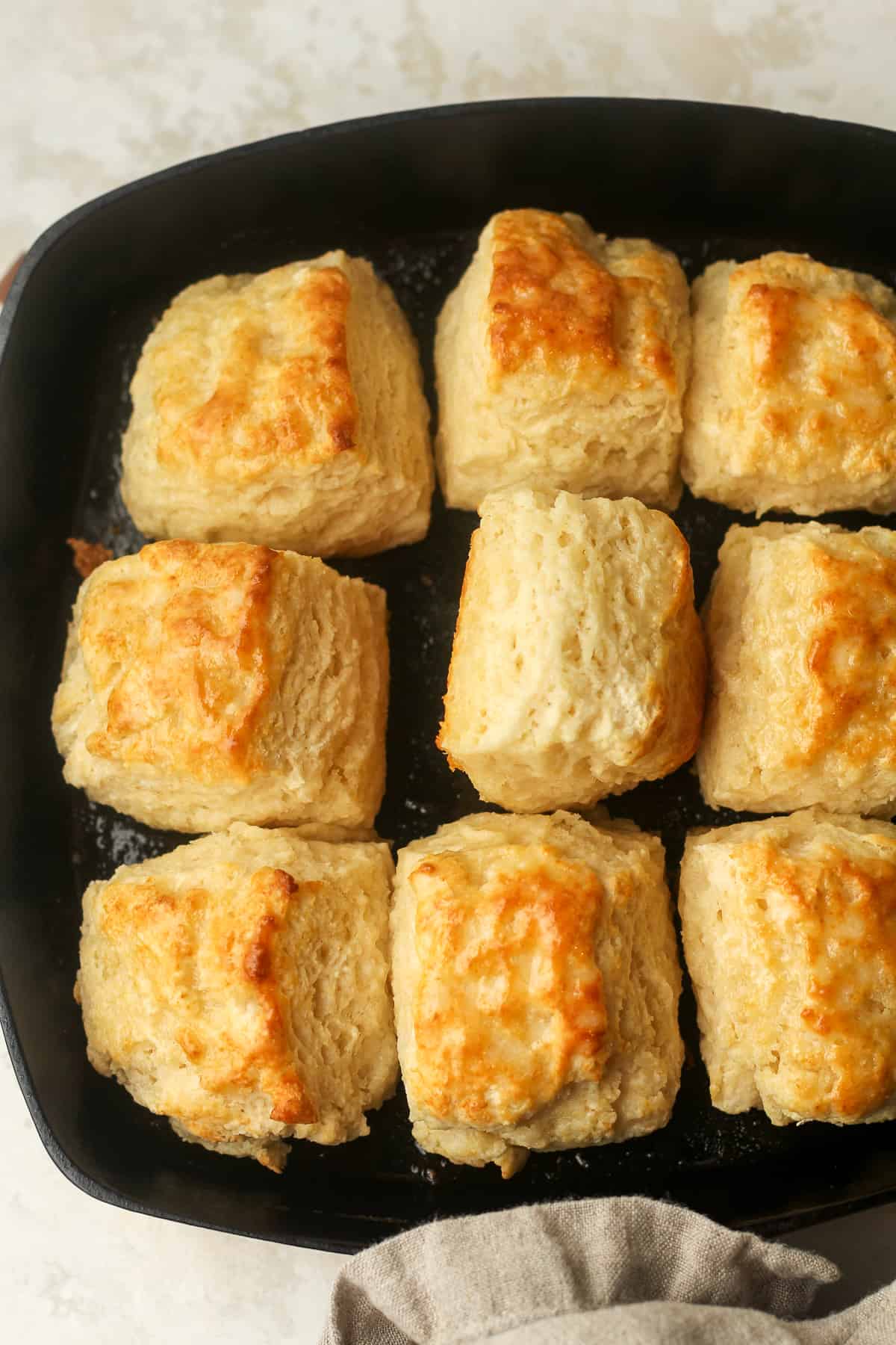A cast iron skillet with nine buttermilk biscuits.