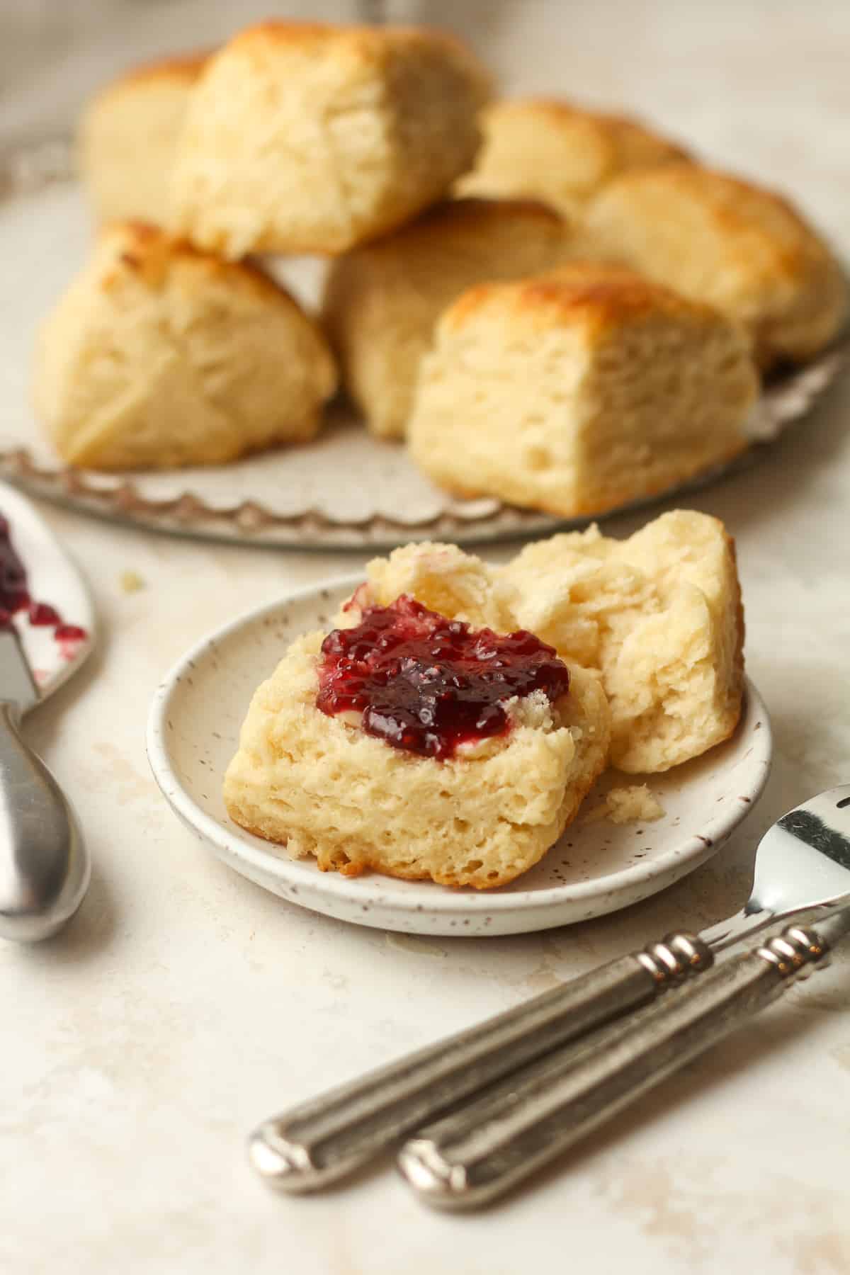 Side view of a biscuit with jam and a plate of biscuits in the background.