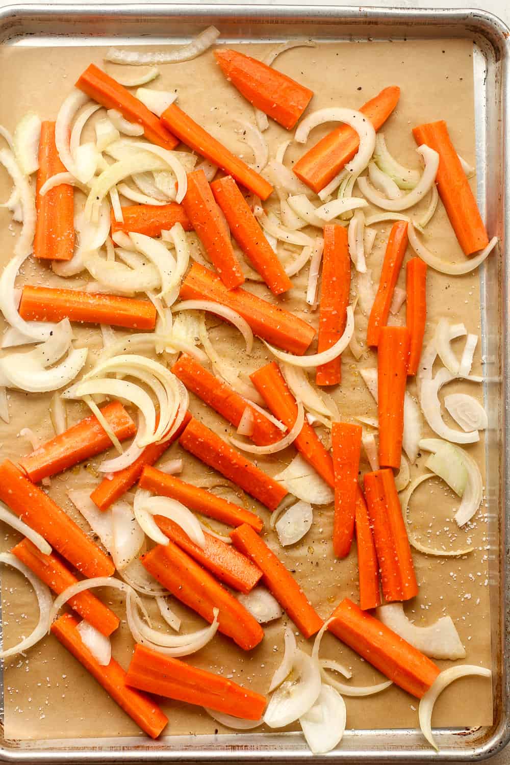 A sheet pan of the raw carrots and onions.