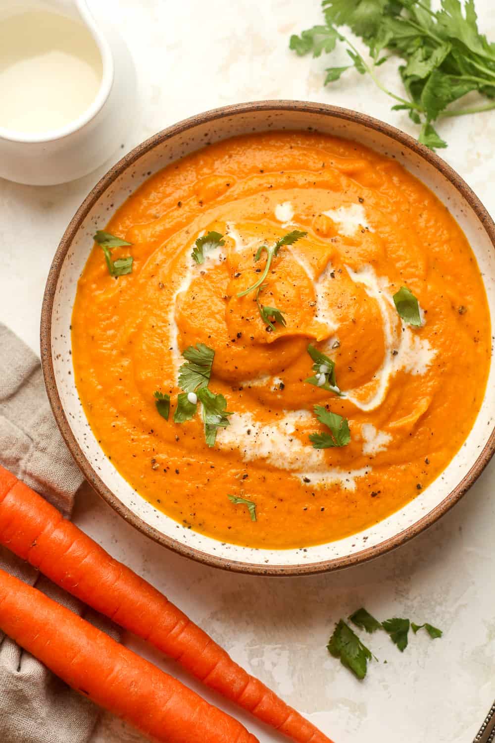 Overhead view of a bowl of carrot soup with cream on top.