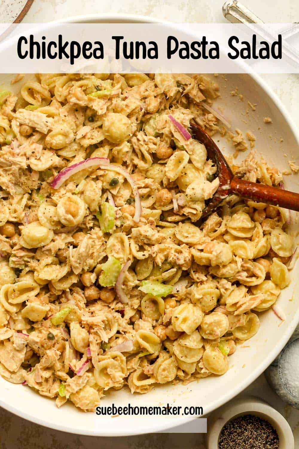 A large bowl of chickpea tuna pasta salad with a wooden spoon.