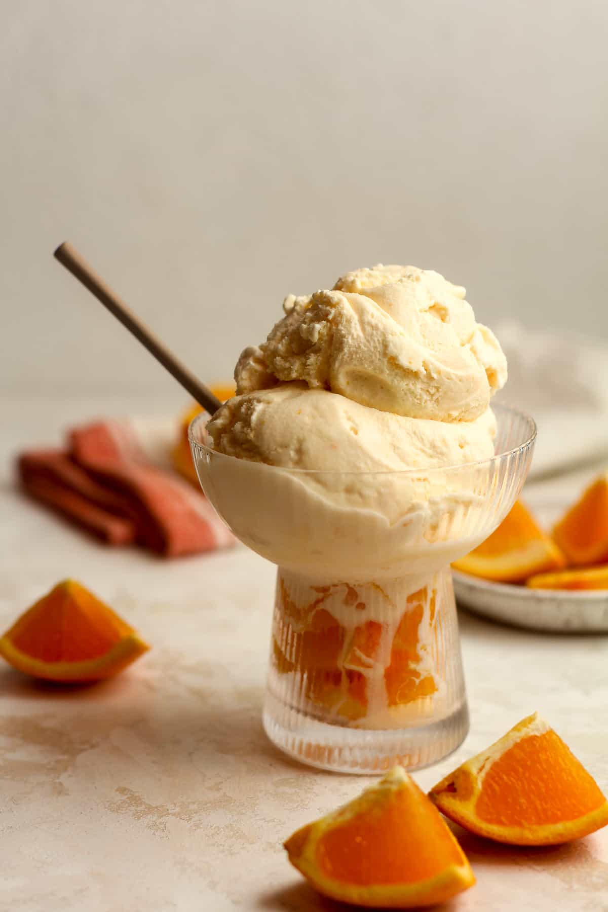 Side view of a bowl of orange creamsicle ice cream with a spoon.