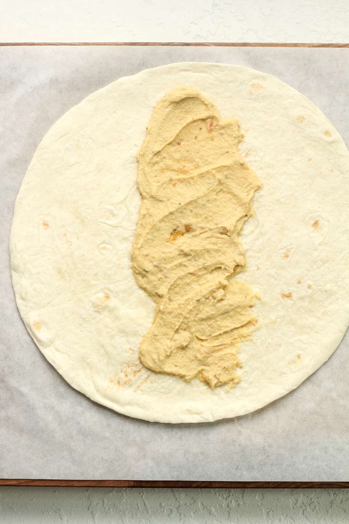 A tortilla with hummus smeared down the middle.