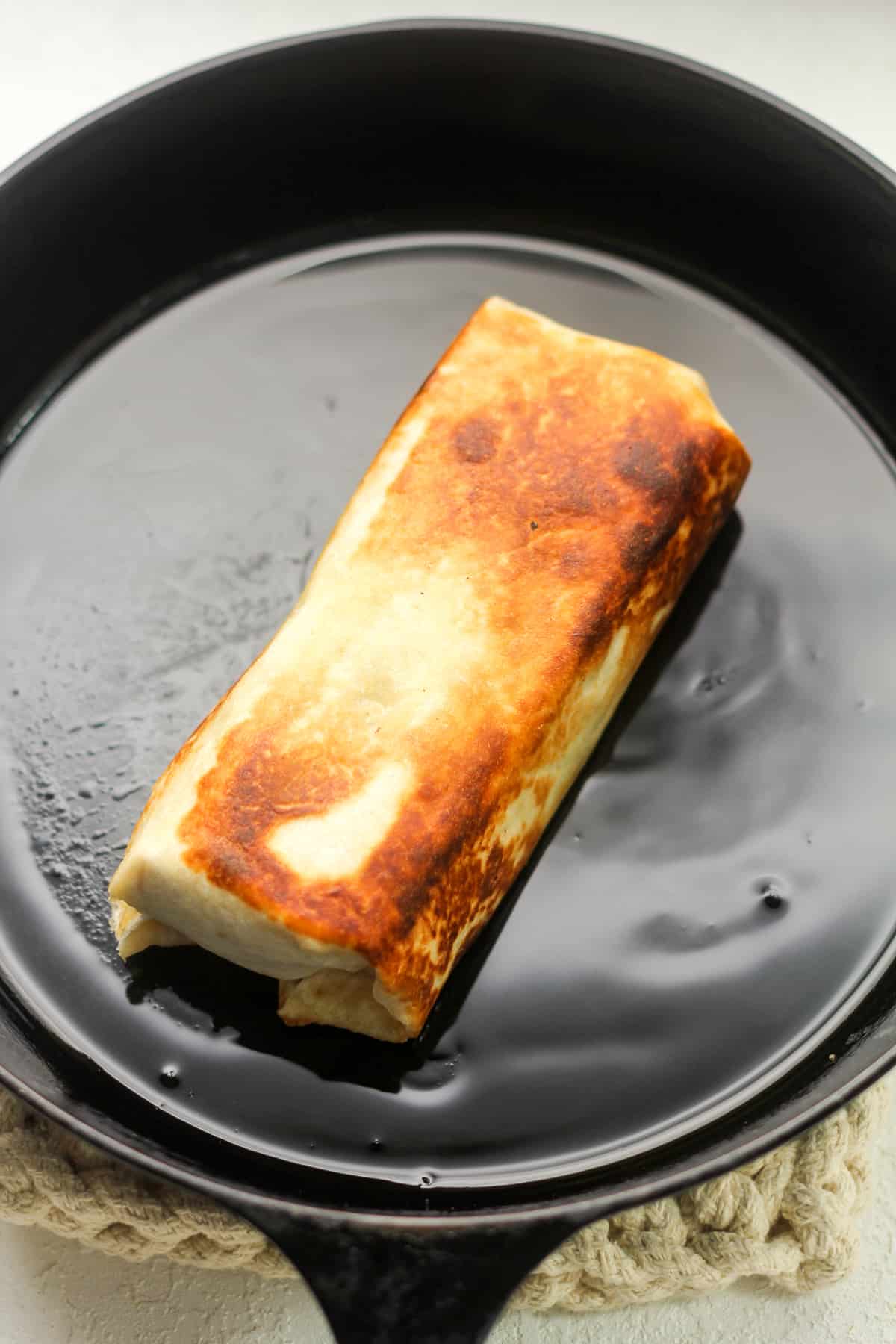 A cast iron skillet with a just sauteed chicken wrap.