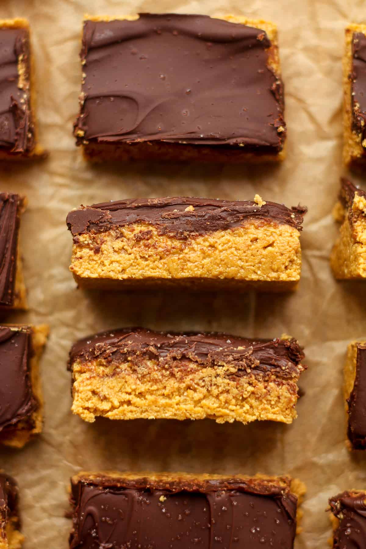 Closeup on some chocolate peanut butter bars, with some showing the sides.