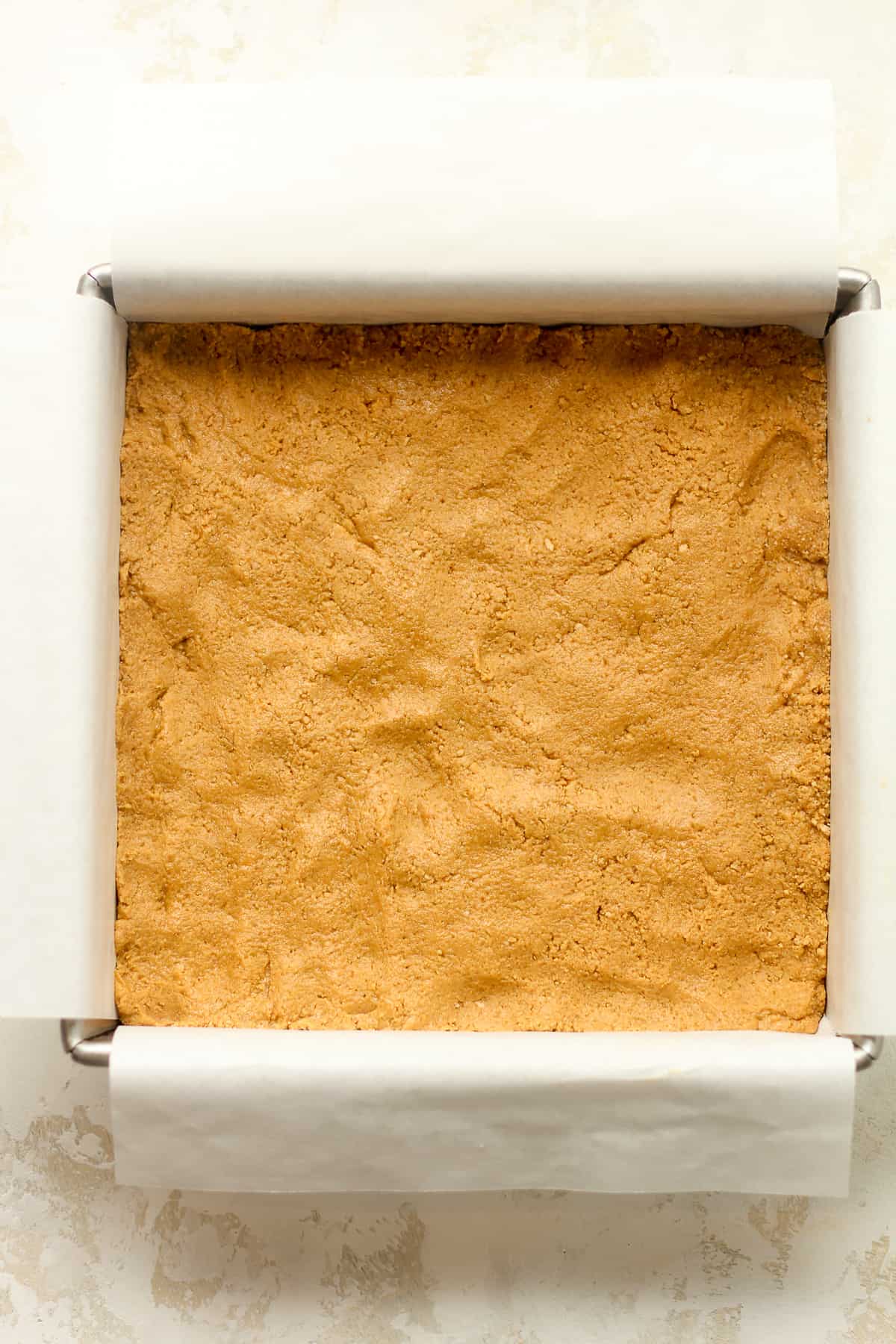 The pressed peanut butter mixture in a square pan.