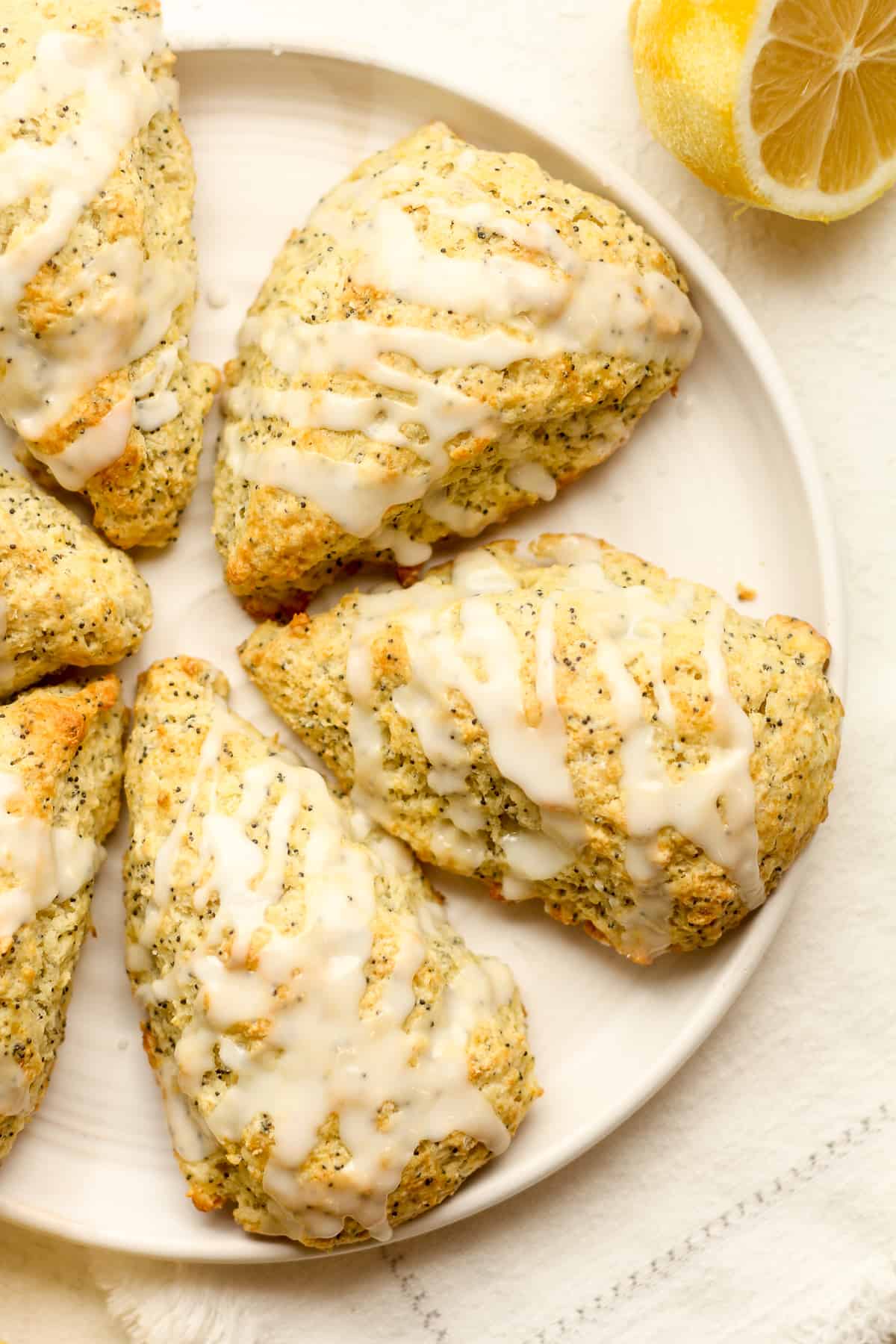 A plate of lemon scones with poppy seeds and glaze.
