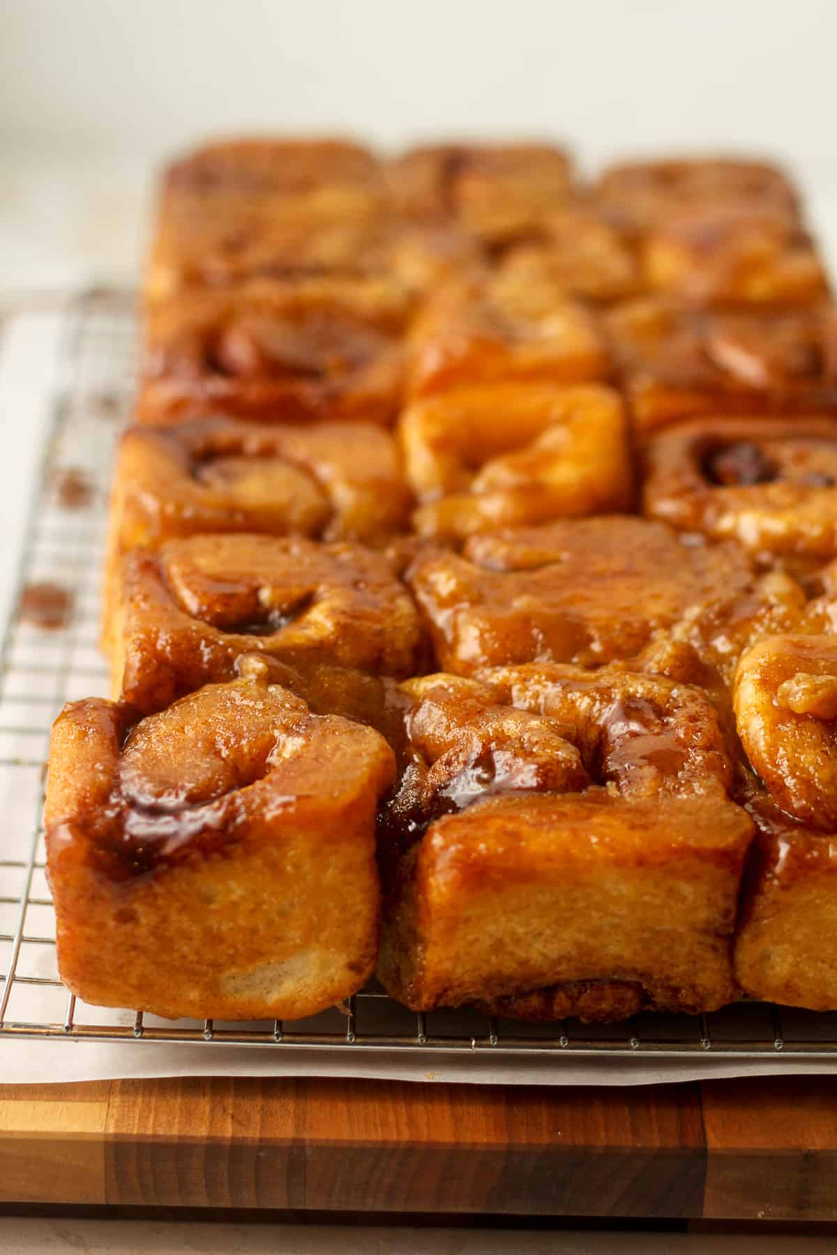Side view of a bunch of old fashioned sticky buns on a wire rack.