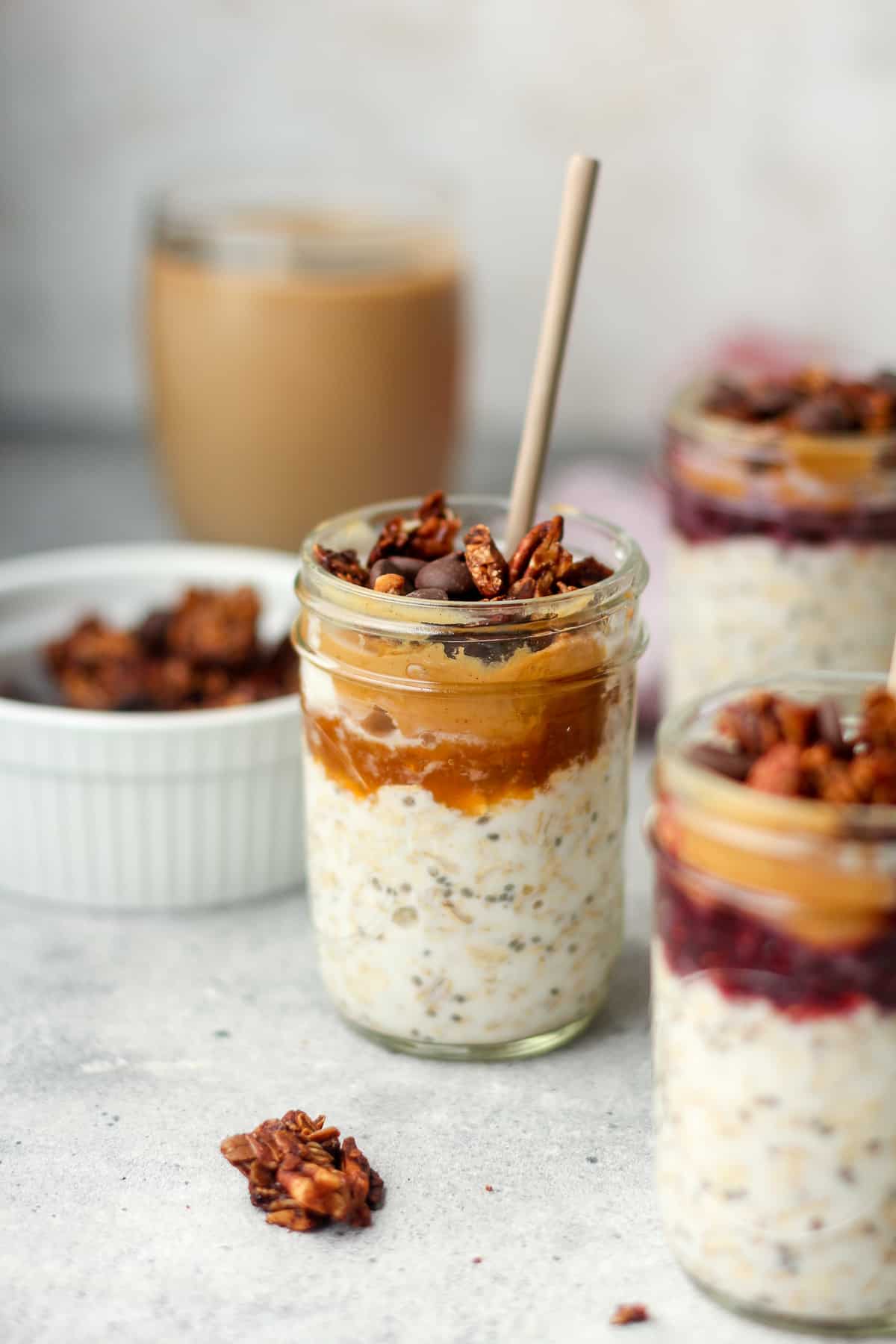 Side view of mason jars of overnight oats topped with pb&j plus granola.