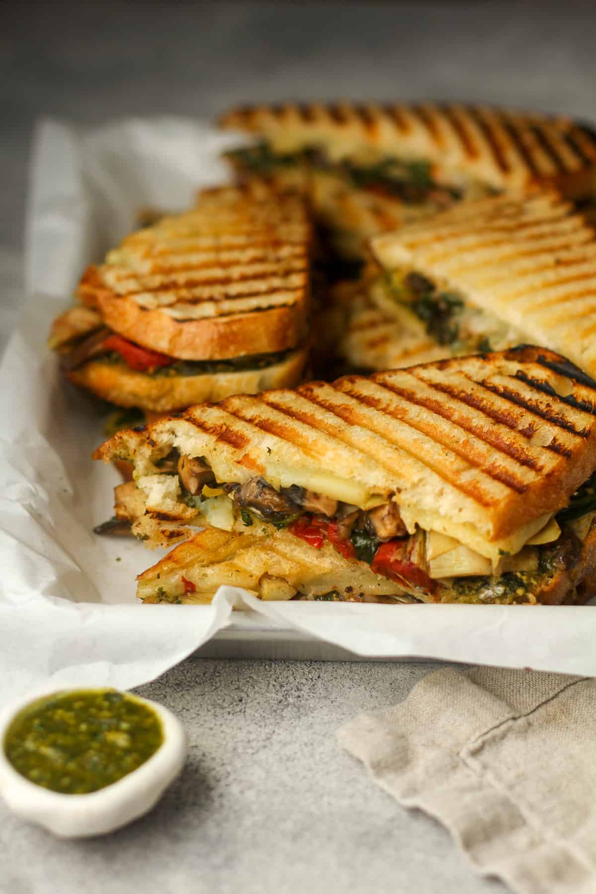Side view of a tray of pesto sandwiches with veggies.