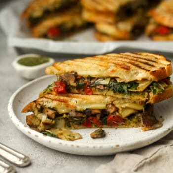 Side view of a stacked California pesto panini on a plate.