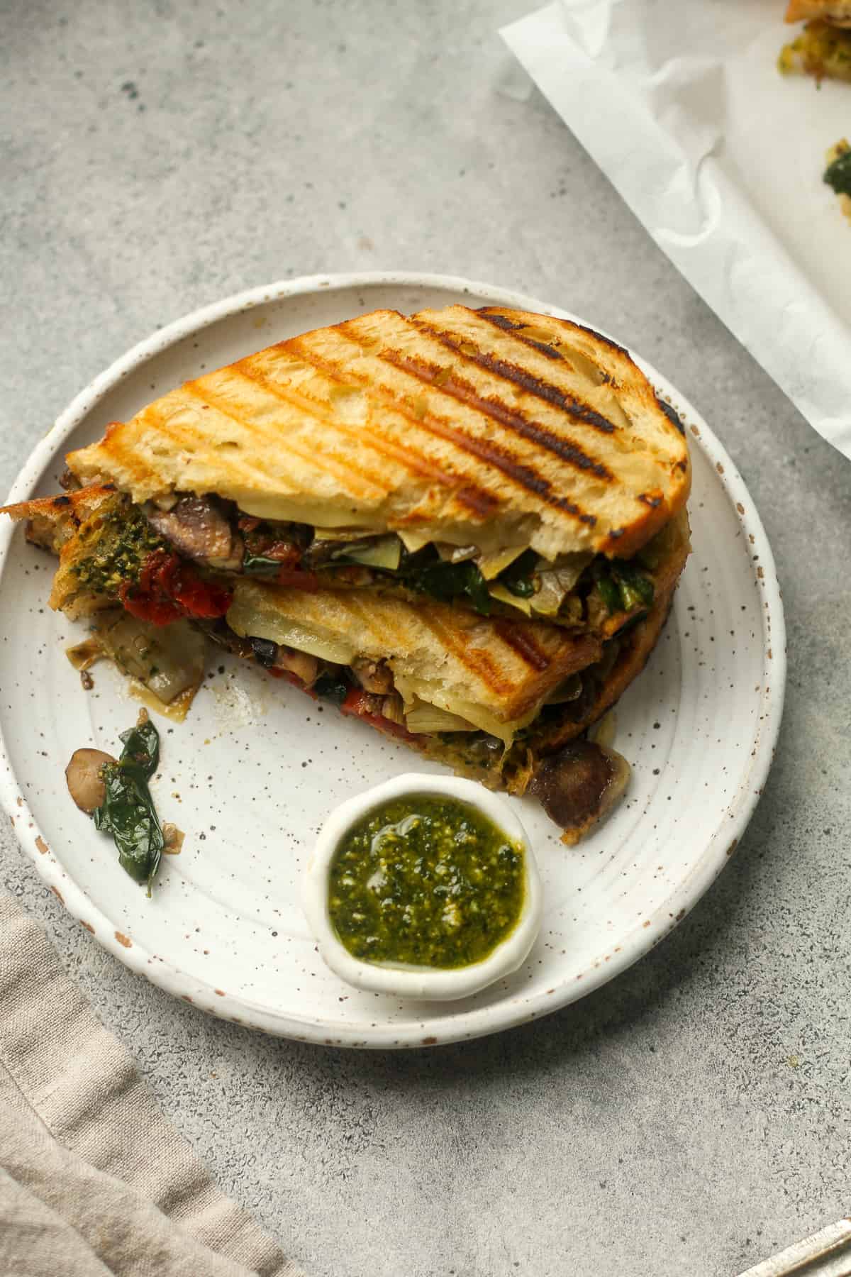 Overhead view of a plate of a sliced pesto veggie sandwich.