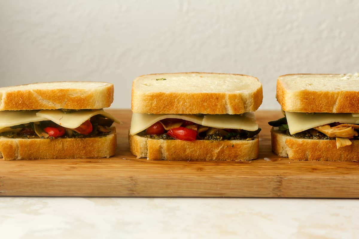 Three sandwiches on a board ready to be grilled.