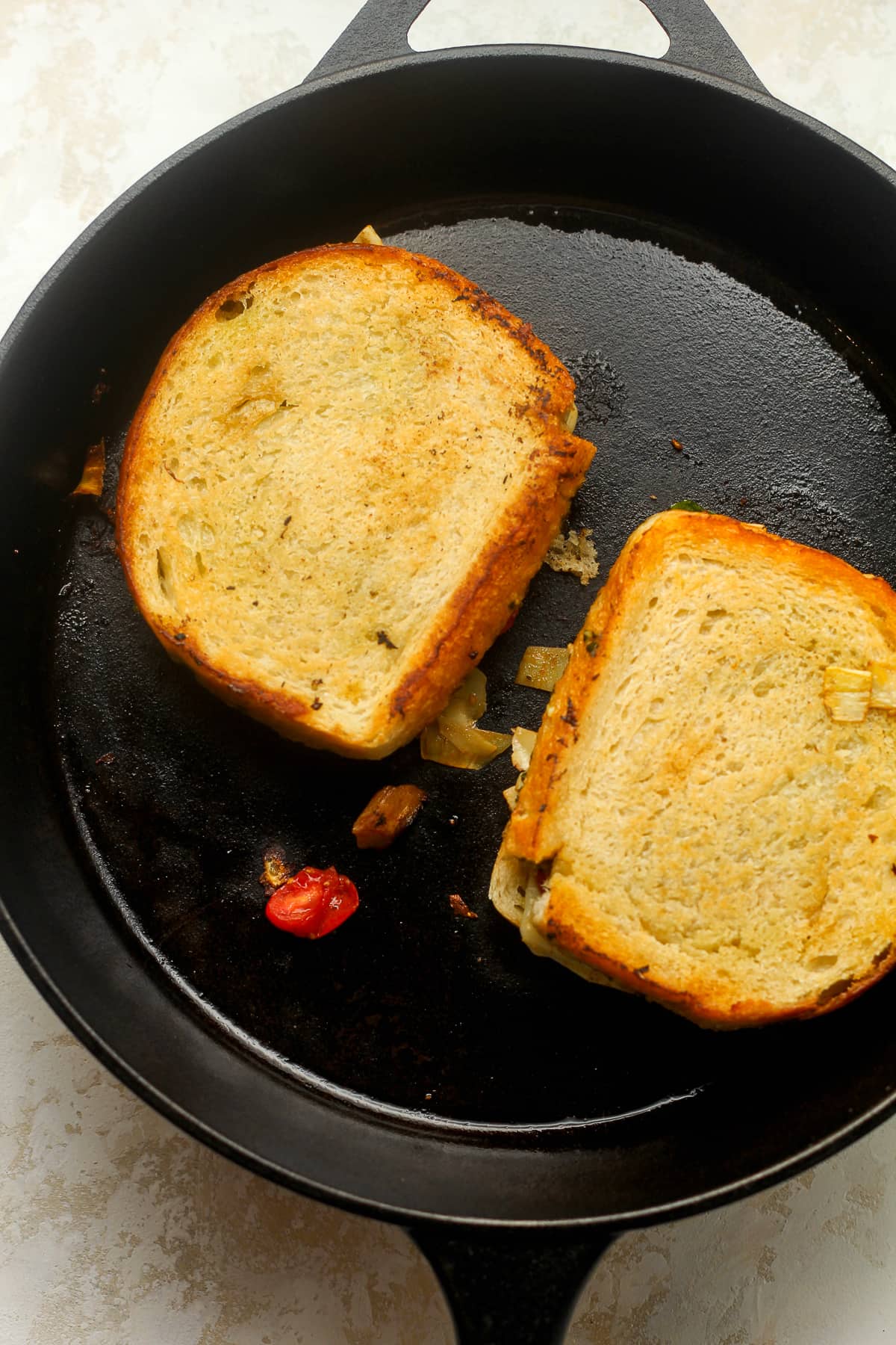 Two grilled sandwiches in a cast iron skillet.