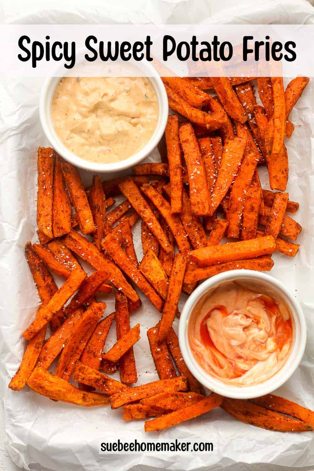 Overhead of a tray of spicy sweet potato fries with bowls of dipping sauce.