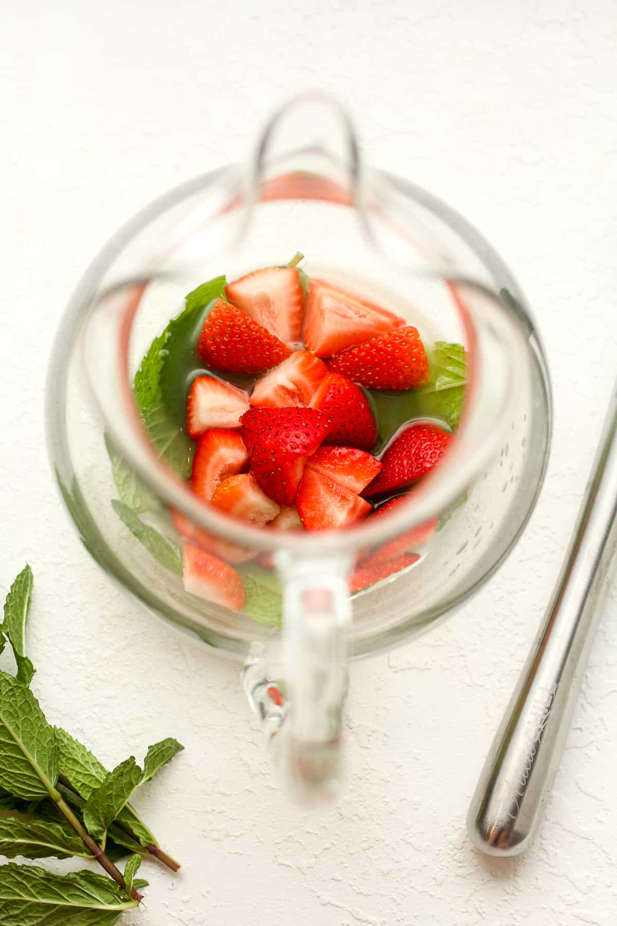 The pitcher with the strawberry slices and mint leaves.