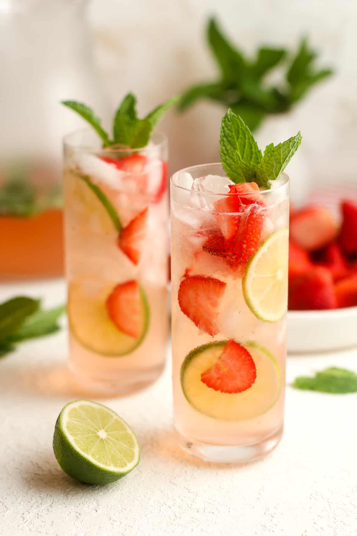 Two mojito mocktails with strawberries and mint.