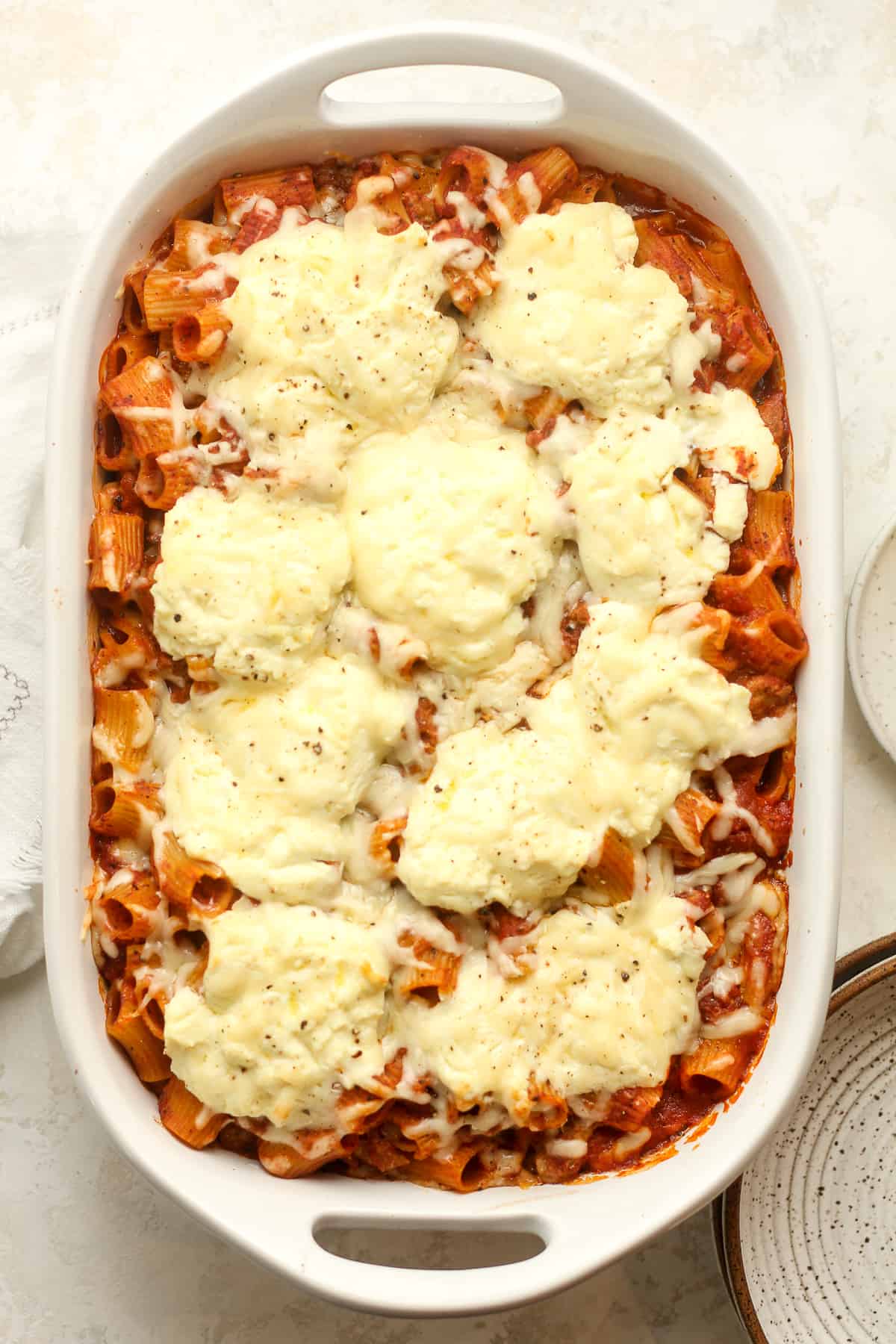 A casserole dish of baked rigatoni with dollops of ricotta cheese.