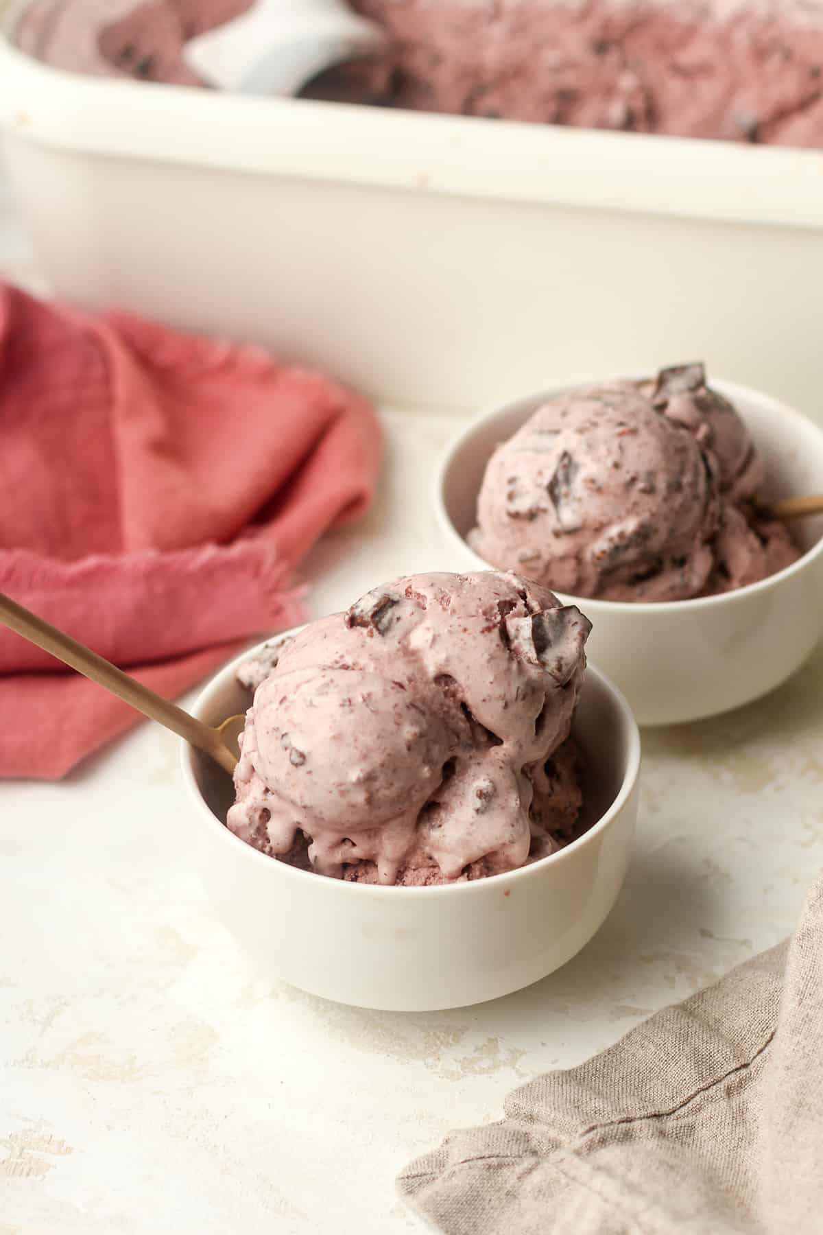 Two small bowls of cherry ice cream with brownie chunks.