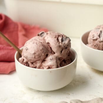 Side view of two bowls of black cherry ice cream with chocolate chunks.