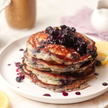 A plate of blueberry pancakes with lemon, topped with blueberry compote.