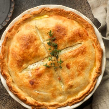 Closeup on a double crust pot pie with sprigs of thyme.