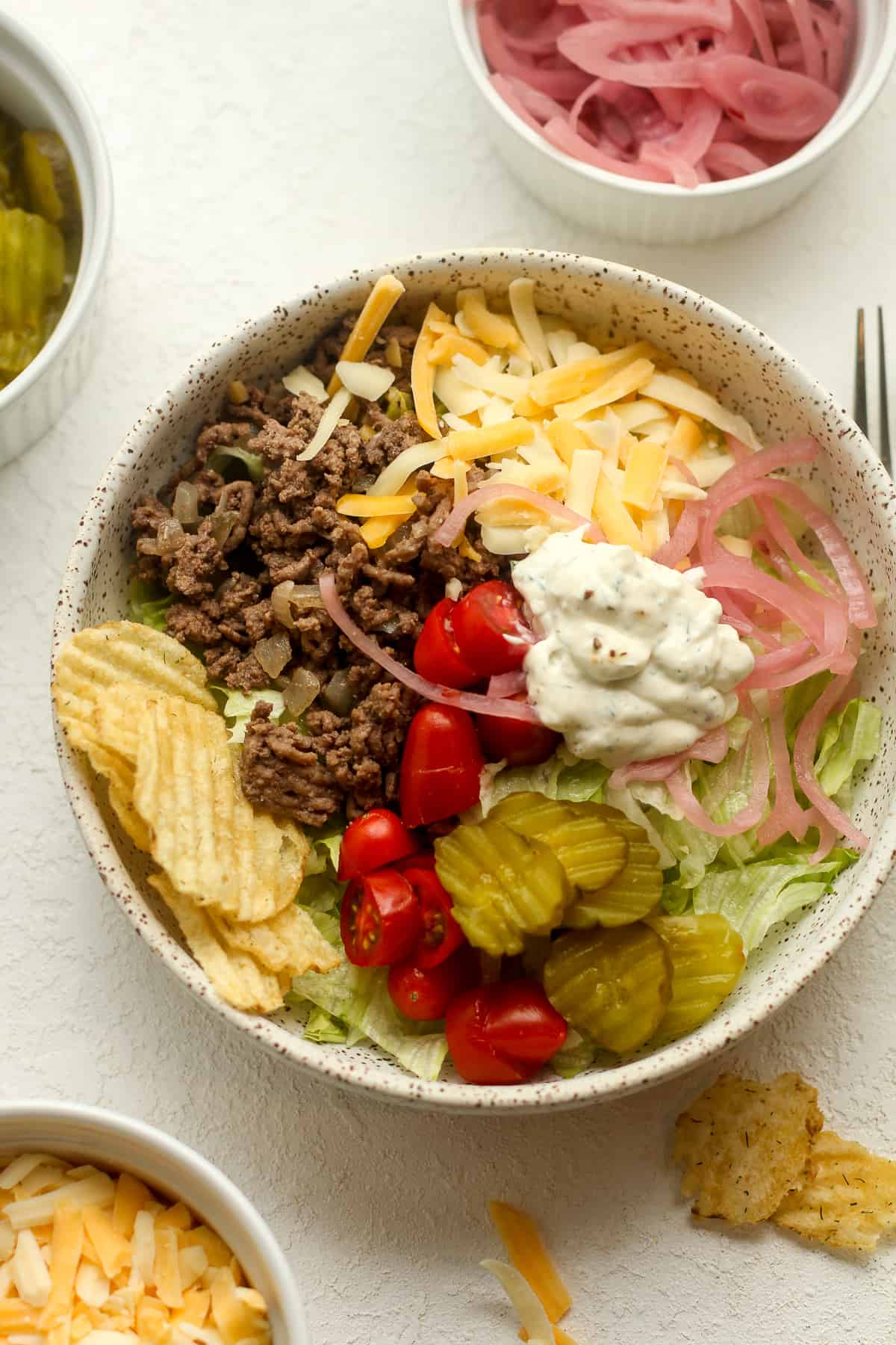 A bowl of the burger bowl by ingredient with the dill ranch on top.
