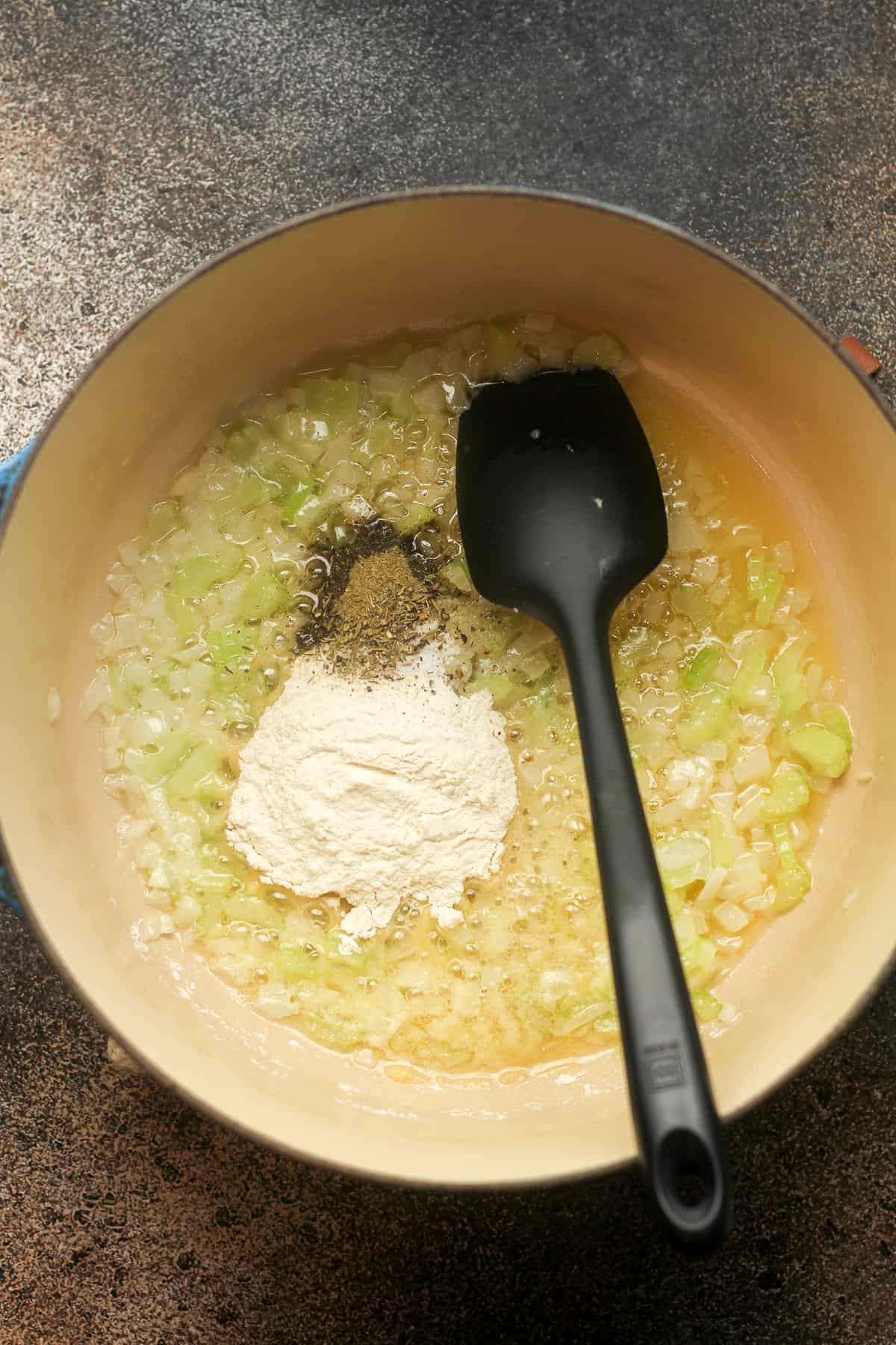 A pot of the sauteed onion and celery plus the flour and seasonings on top.