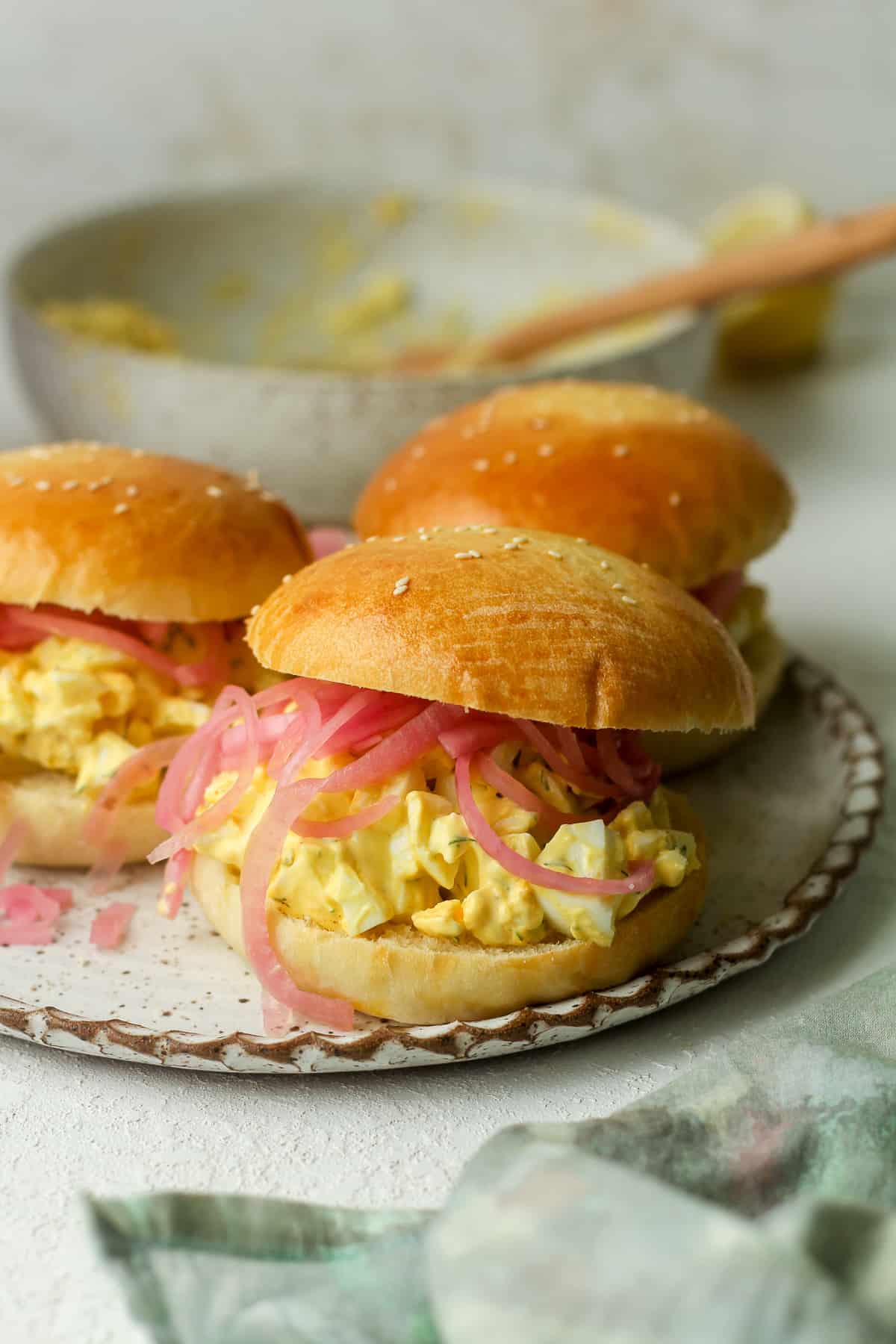 Side view of a plate of egg salad sandwiches with a green napkin.