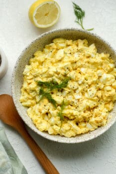 A bowl of creamy egg salad with dill on top.