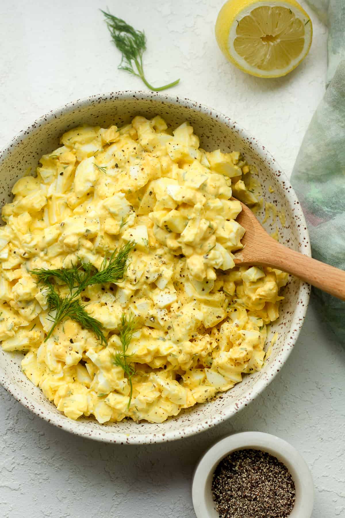 A bowl of egg salad with a wooden spoon.