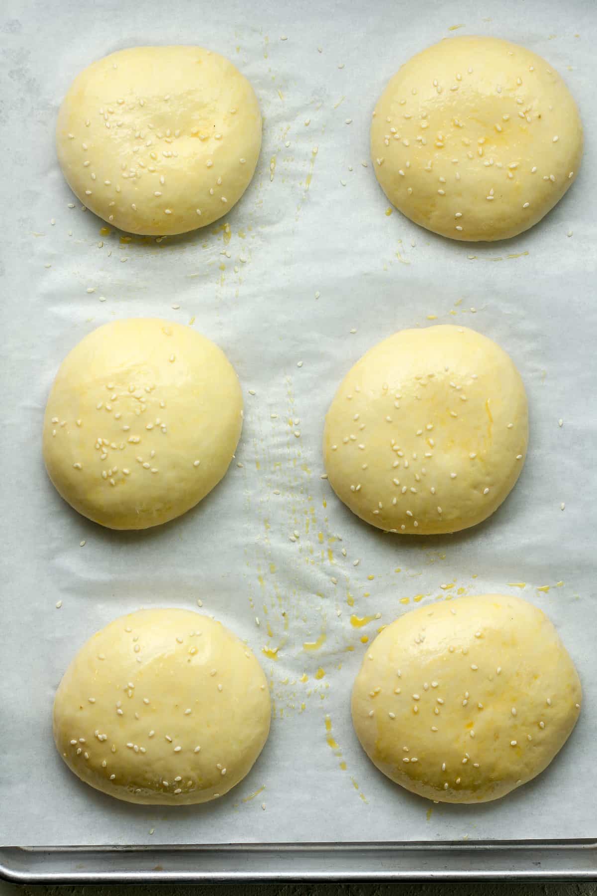 A pan of six brioche buns before baking.