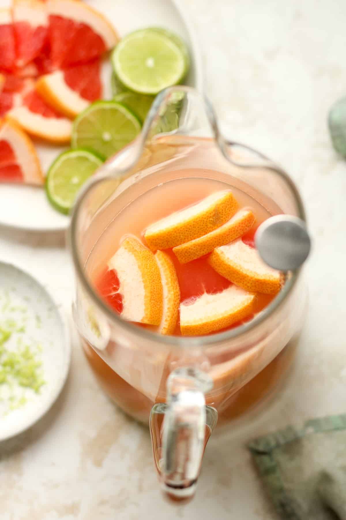 A pitcher of Paloma cocktail with grapefruit slices.