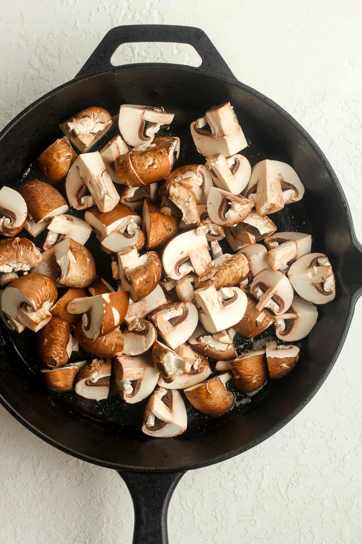 A skillet of quartered mushrooms.