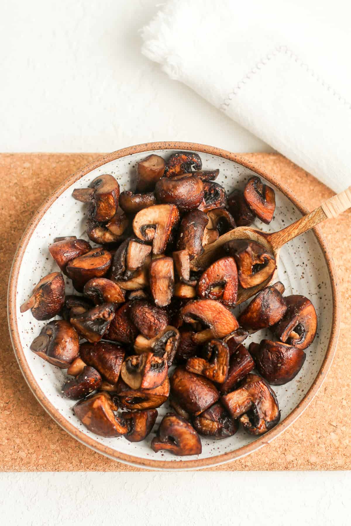 A bowl of browned mushrooms on a wooden board.