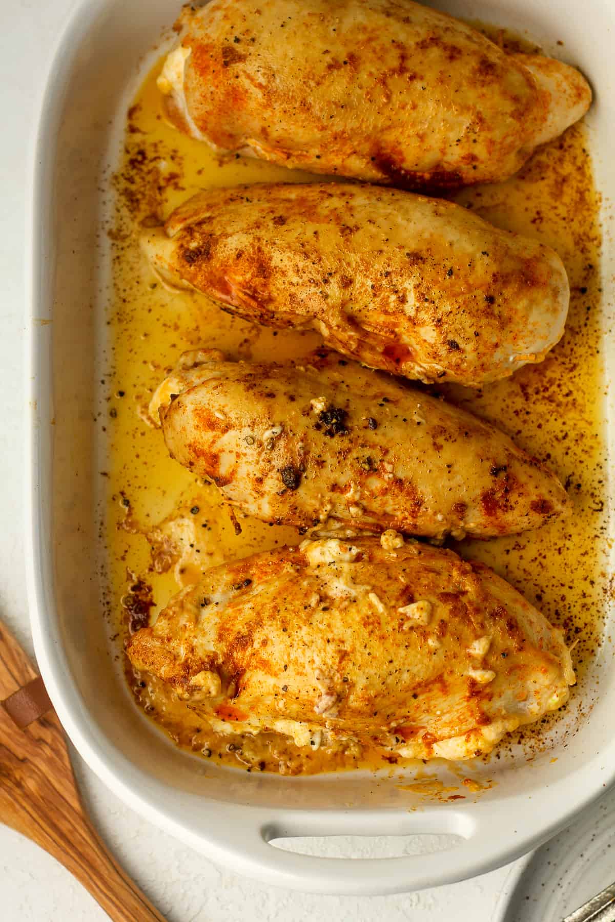 A casserole with four seared stuffed chicken breasts.