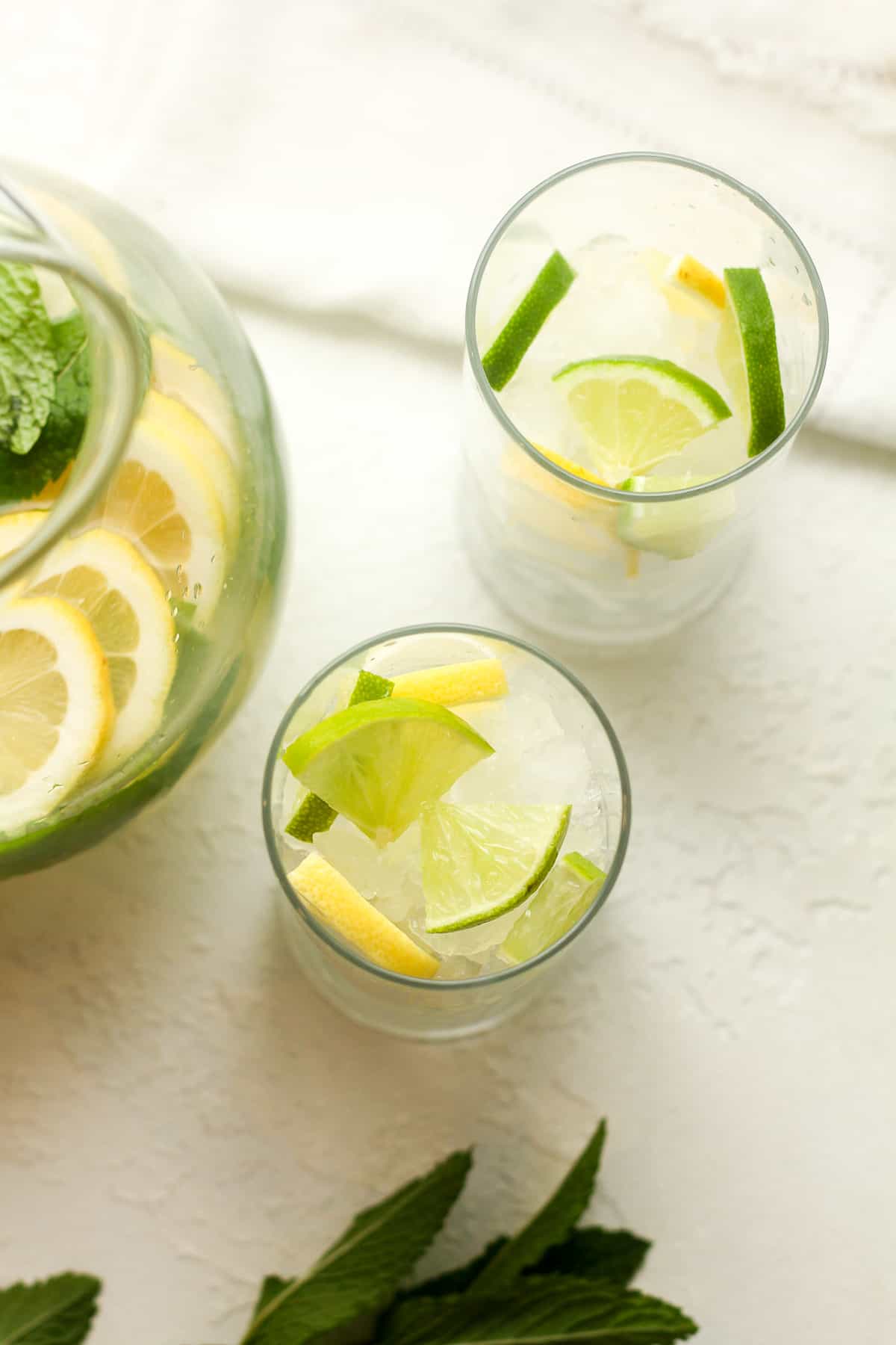Overhead shot of two glasses with lemon and lime slices plus grated ice.