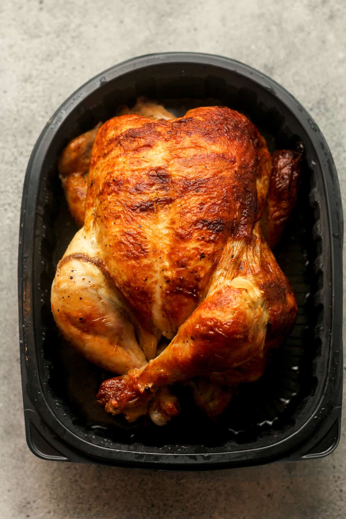 A whole rotisserie chicken in a throwaway container.