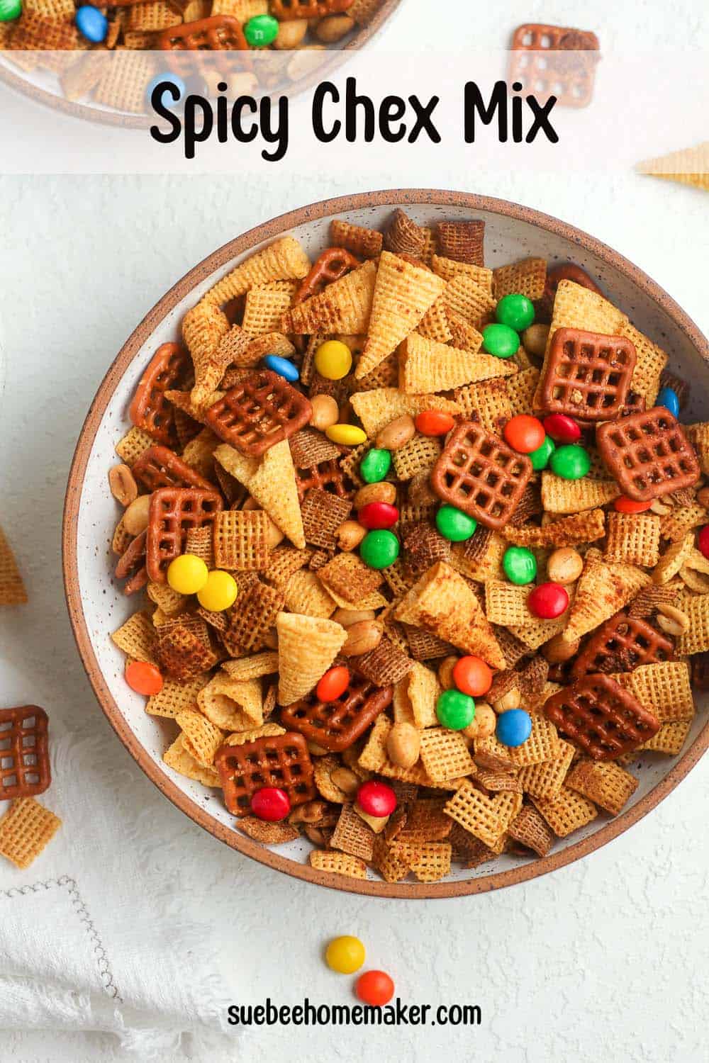 A bowl of the spicy chex mix on a white surface.