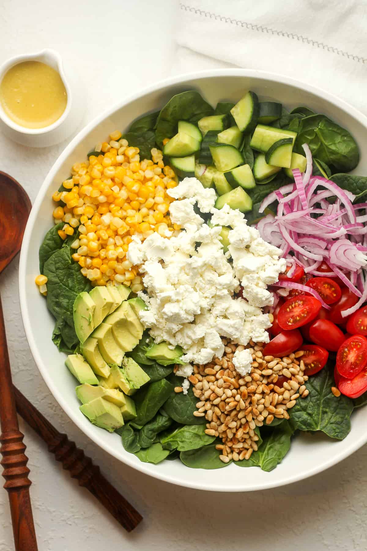 A bowl of the spinach salad with toppings separated by ingredients.