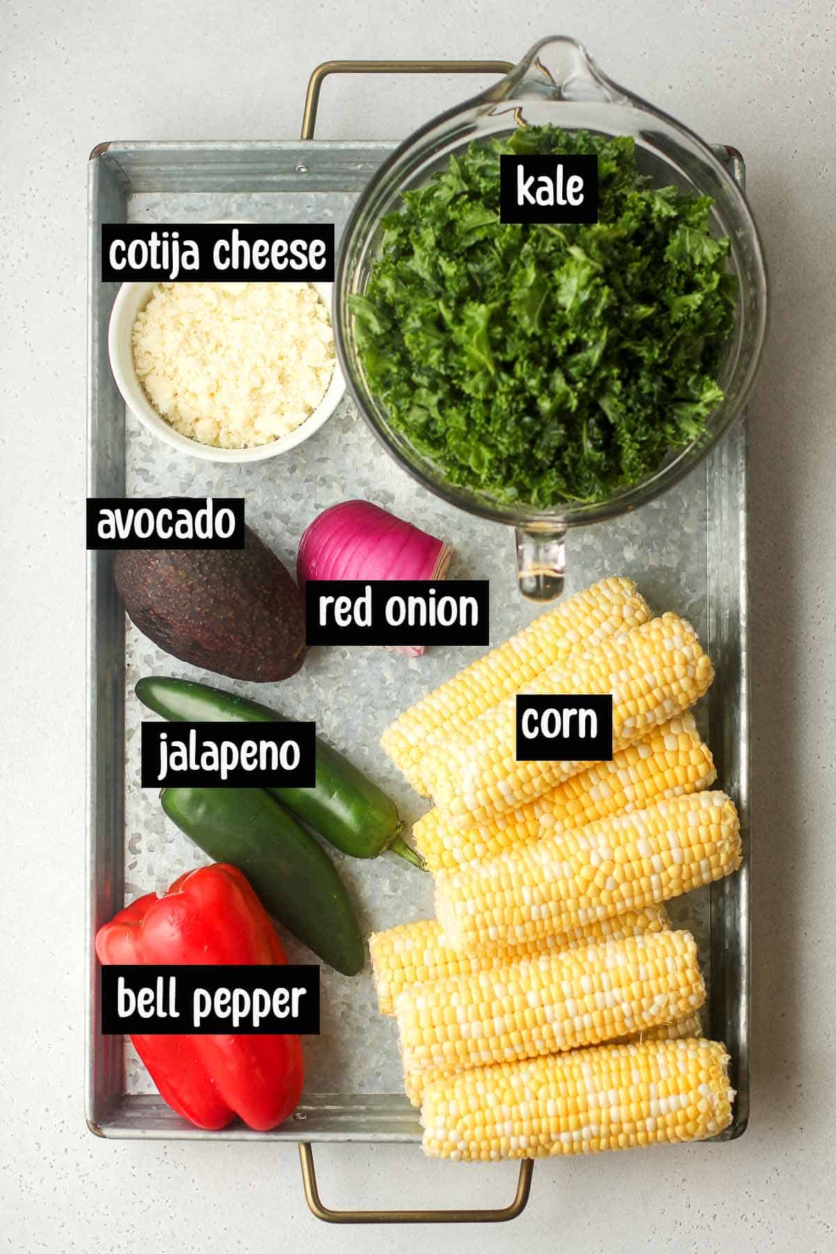 A tray of labeled ingredients for the Mexican street corn kale salad.