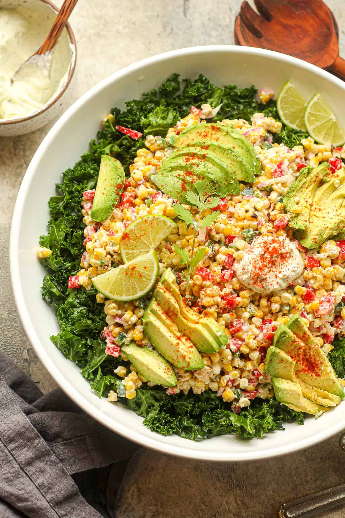 Overhead view of a serving bowl of kale salad topped with Mexican street corn and avocado slices.