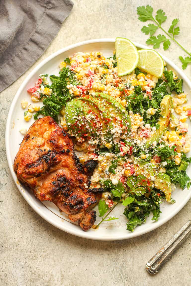 A serving of grilled chicken and some street corn salad with avocado.