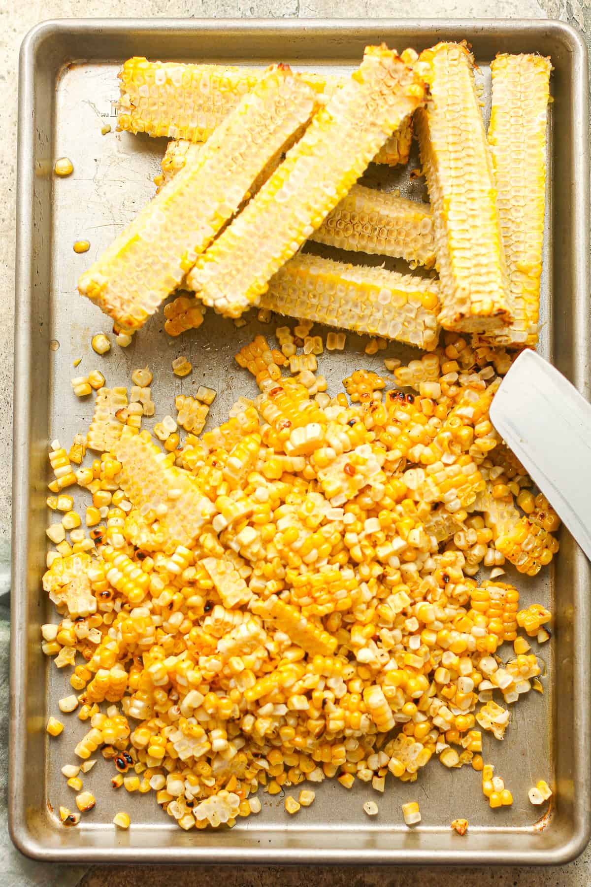 A pan of corn cobs and corn kernels sliced off the cobs.