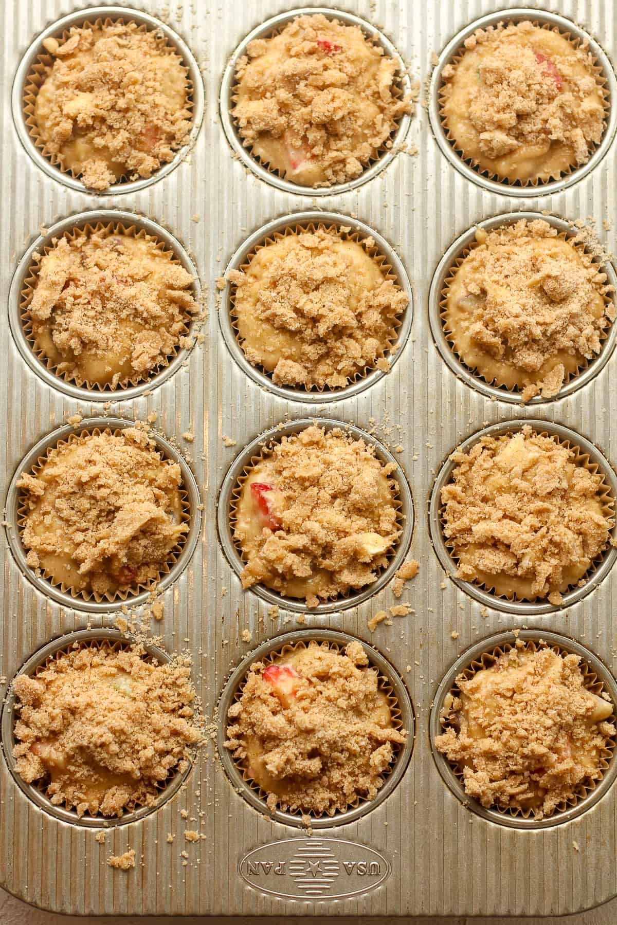 A 12-cup muffin tin with the batter plus streusel topping inside it.