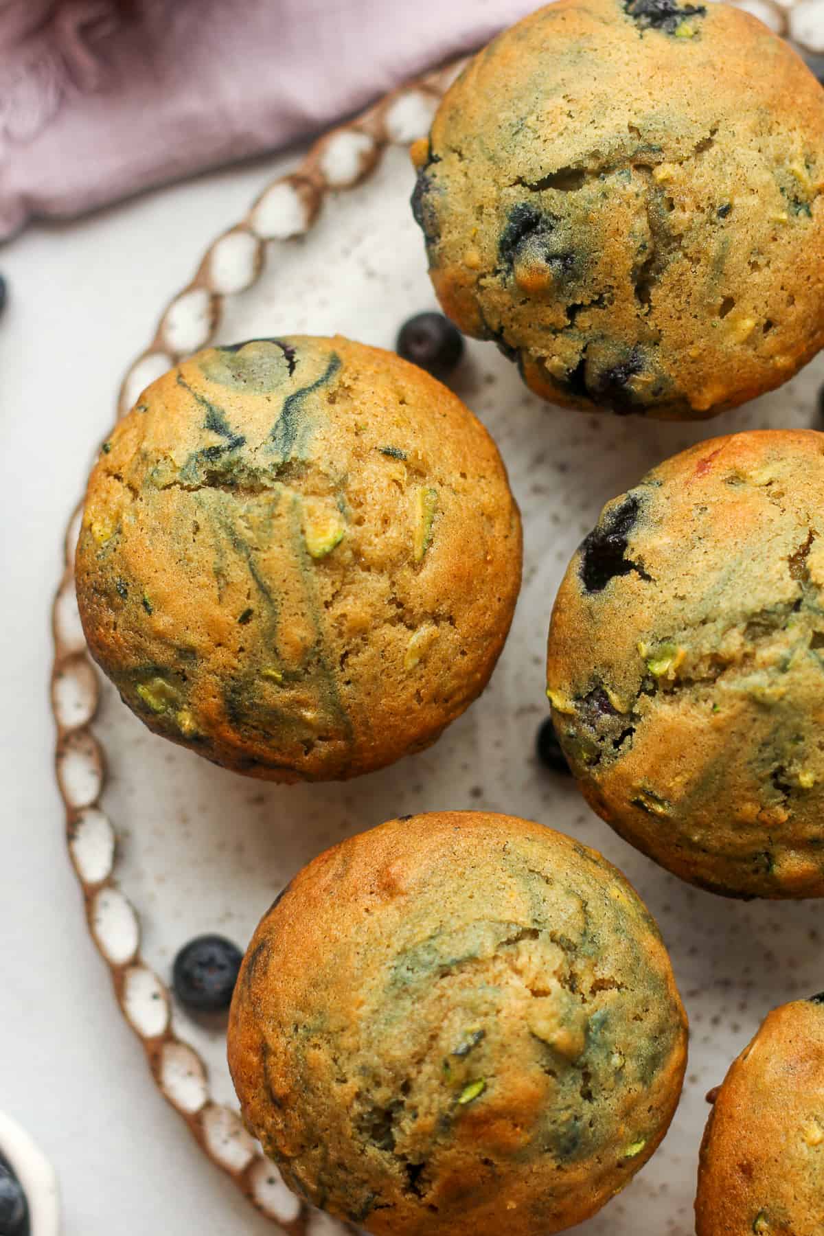 Some blueberry zucchini muffins on a plate.