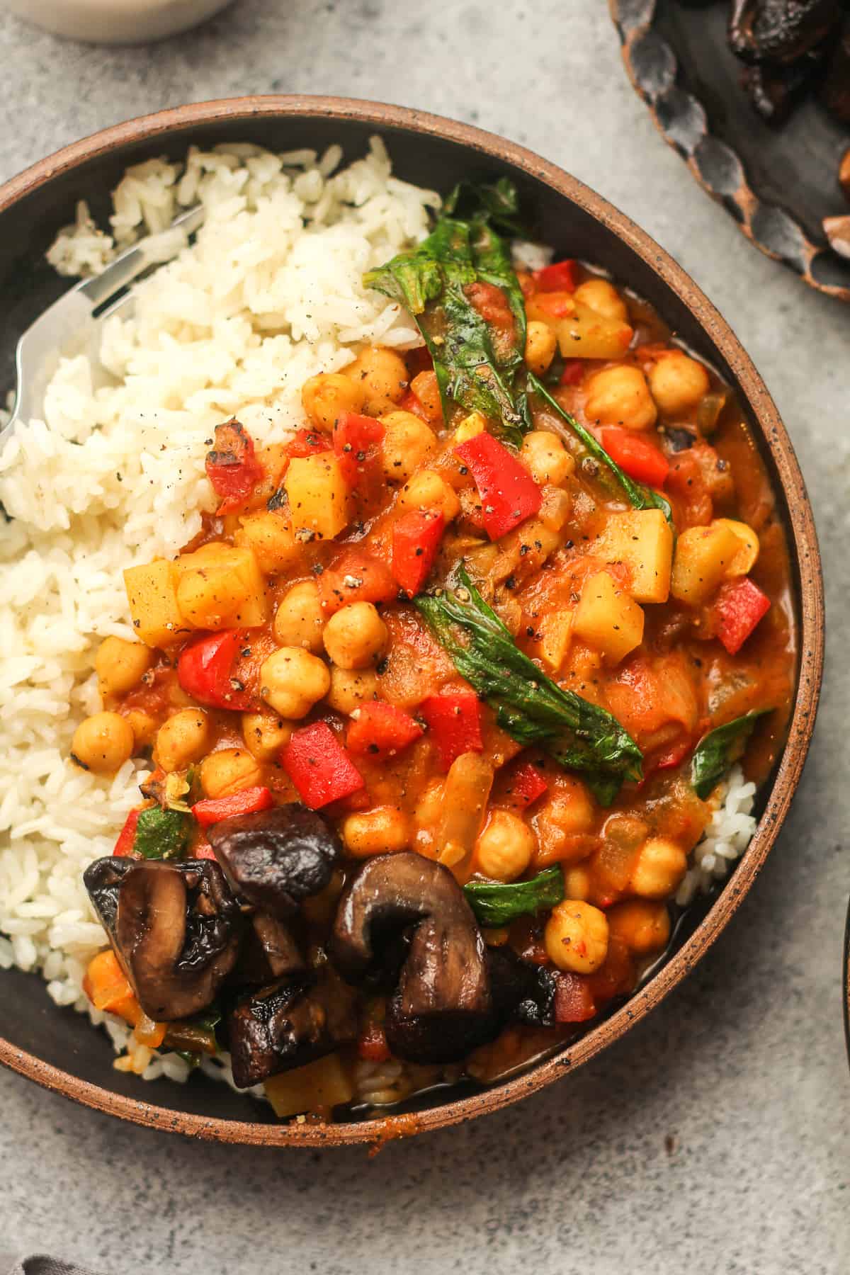 A bowl of rice topped with curried chickpeas and spinach.