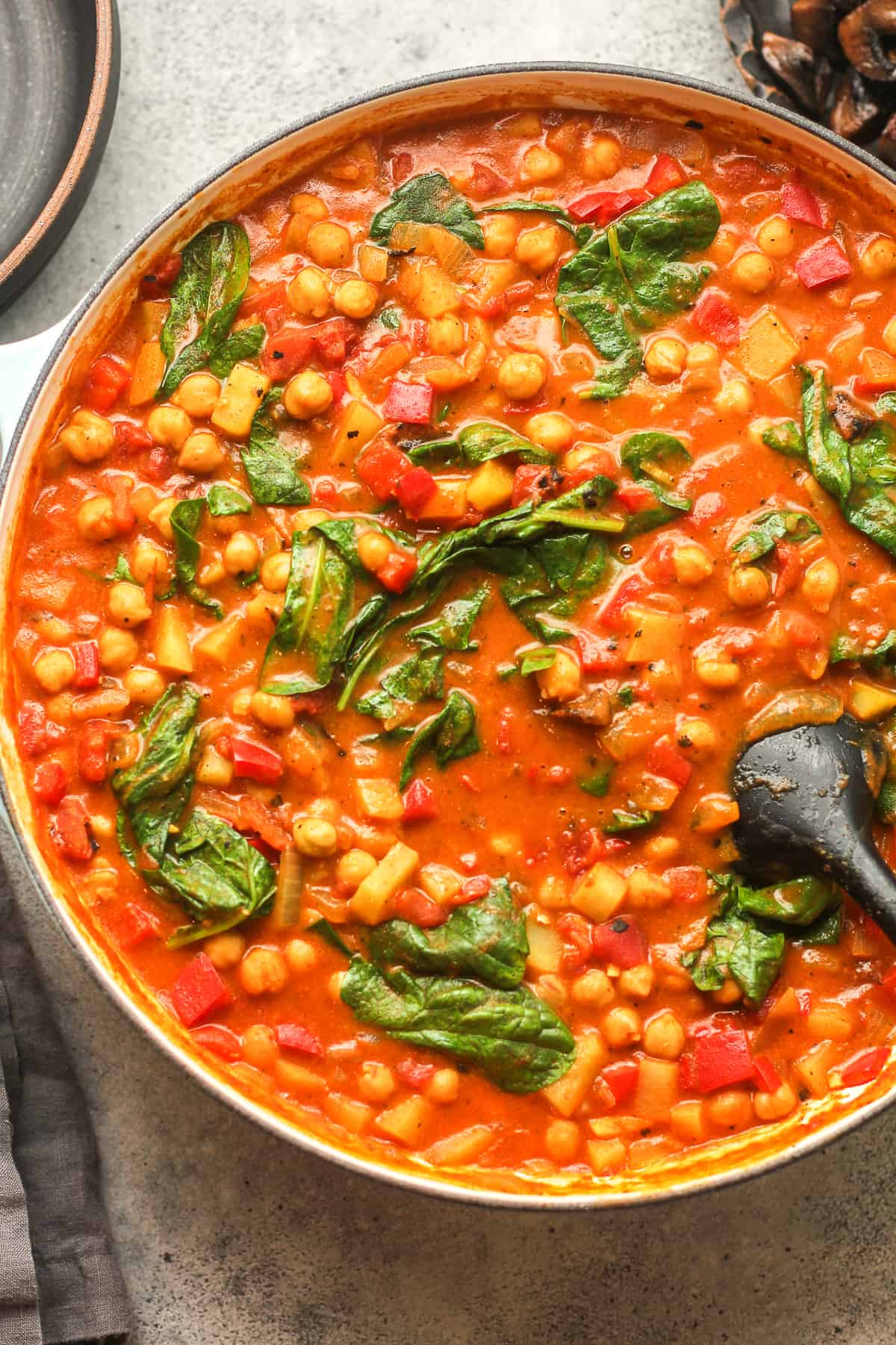 A large pot of chickpea spinach curry on a gray surface.