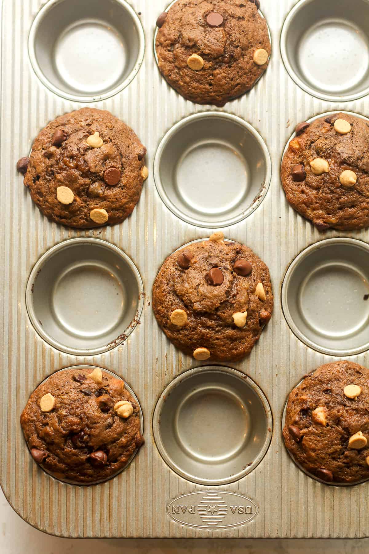 Overhead view of a 12-cup tin of muffins, half full.