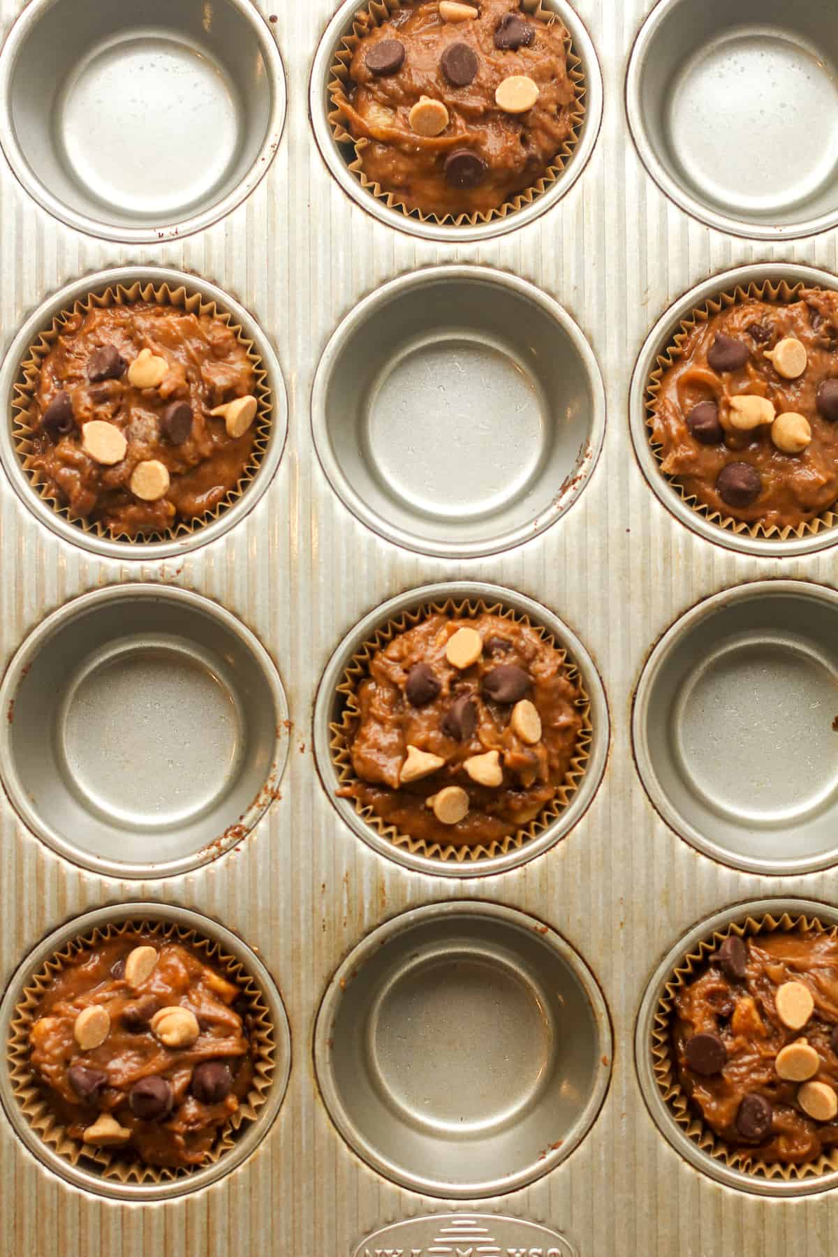 The 12-cup muffin tin with half of them full of muffin batter.